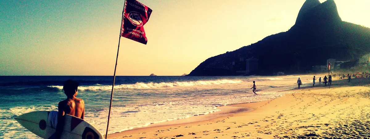 Ipanema Beach at sunset with the twin peaks of Morro Dois Irmãos silhouetted at the far end of the sand