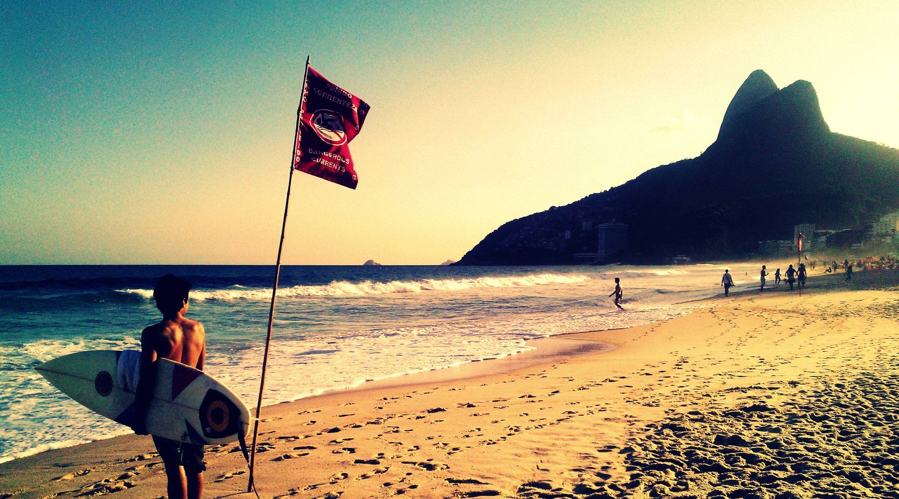 Ipanema Beach at sunset with the twin peaks of Morro Dois Irmãos silhouetted at the far end of the sand