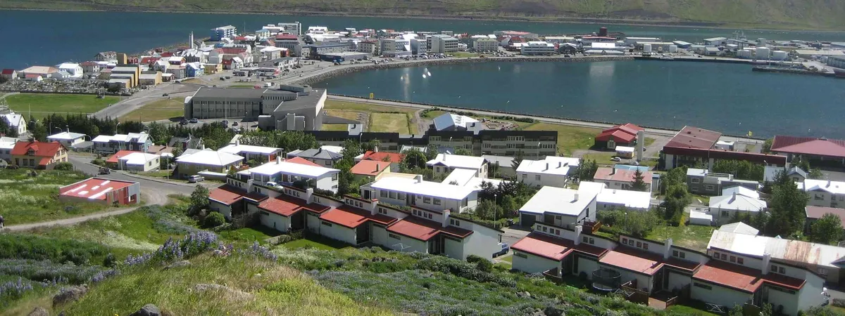 Ísafjörður spread across its sandspit in Skutulsfjörður, with the harbor basin in the middle and flat-topped fjord walls behind