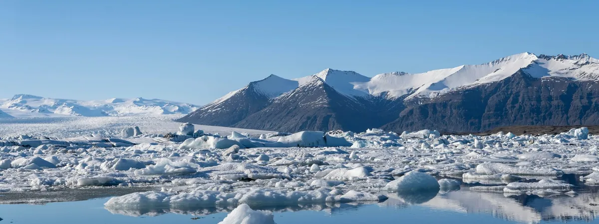 White icebergs drifting on Jökulsárlón's still water, snow-capped mountains reflected behind them