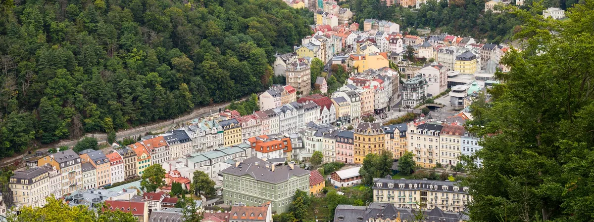 An elevated view of Karlovy Vary's pastel spa hotels packed into the wooded Teplá river valley