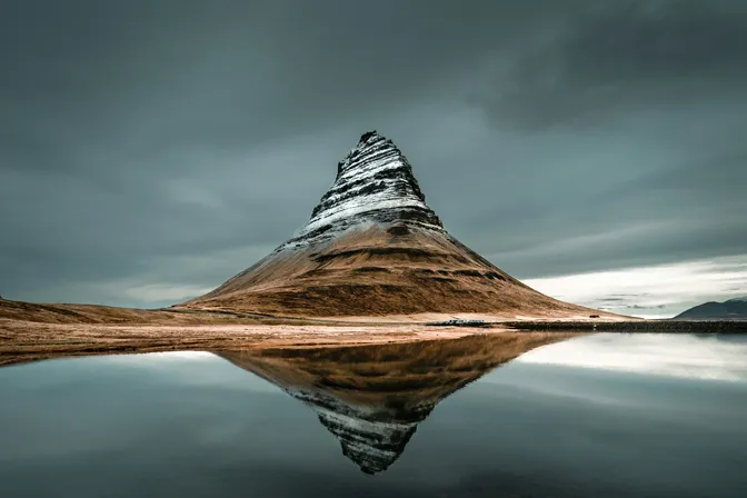 Kirkjufell mountain's distinctive peak mirrored perfectly in the still water below