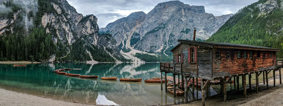 The wooden boathouse and moored rowing boats at Lago di Braies, the Seekofel closing the far end of the lake