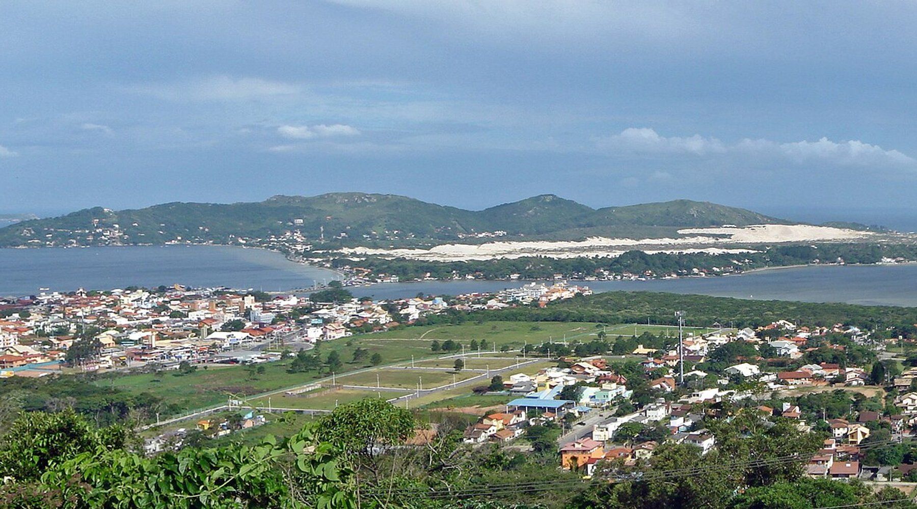 Vista aérea del pueblo junto a la laguna de Lagoa da Conceição, con las dunas de arena y las colinas boscosas de la isla detrás