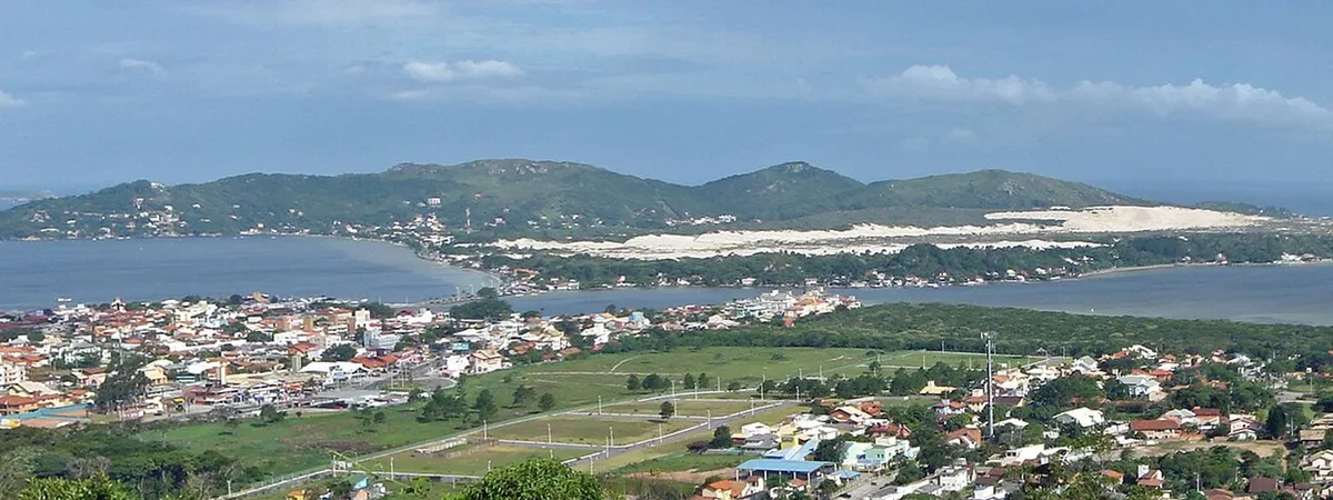 An aerial view over Lagoa da Conceição's lagoon village, with the sand dunes and forested hills of the island behind it