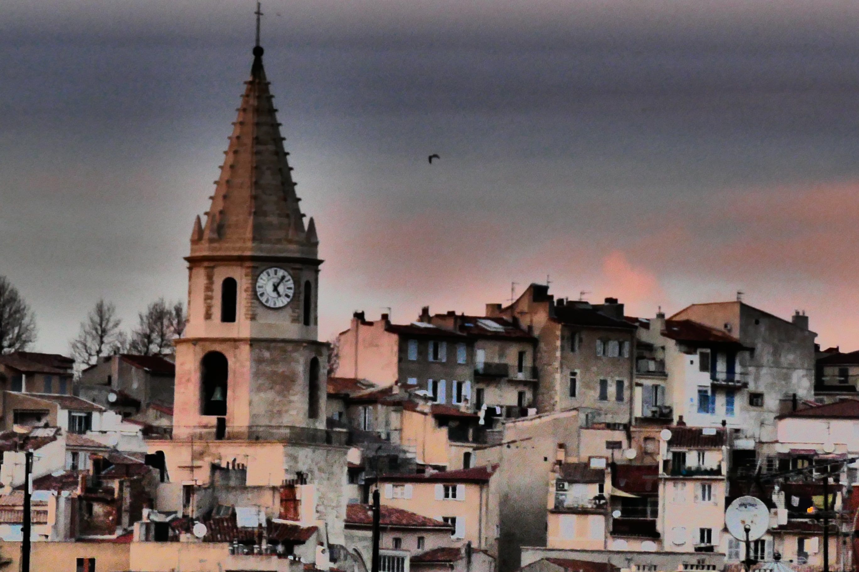The bell tower of Notre-Dame-des-Accoules rising above the rooftops of Le Panier, Marseille's old town, at dusk