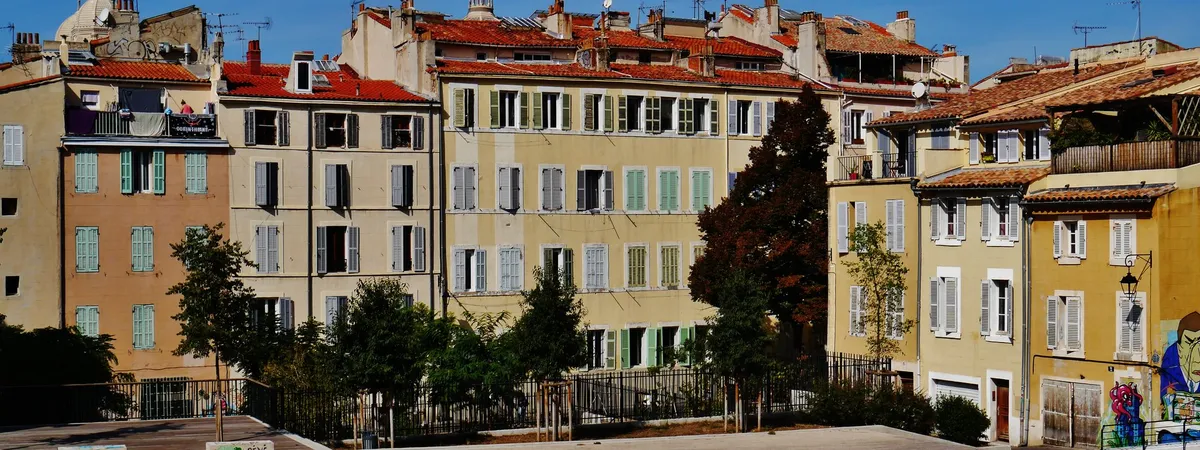 Rooftops and pastel-colored facades of Le Panier, Marseille's old town, with terracotta tile roofs and shuttered windows