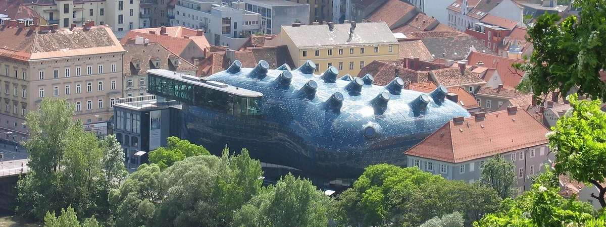 The glass-and-steel Kunsthaus Graz, nicknamed the 'Friendly Alien,' rising above Lend's rooftops beside the Mur River