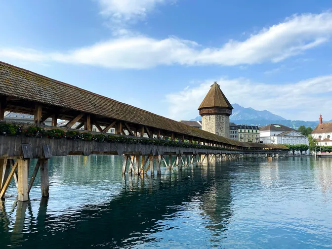The wooden Kapellbrücke crossing the Reuss in Lucerne, with its octagonal water tower and Mount Pilatus beyond