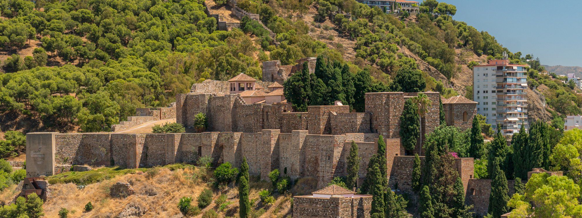 The Alcazaba fortress on its hillside above Málaga's old town, with the Gibralfaro castle walls visible on the summit behind it