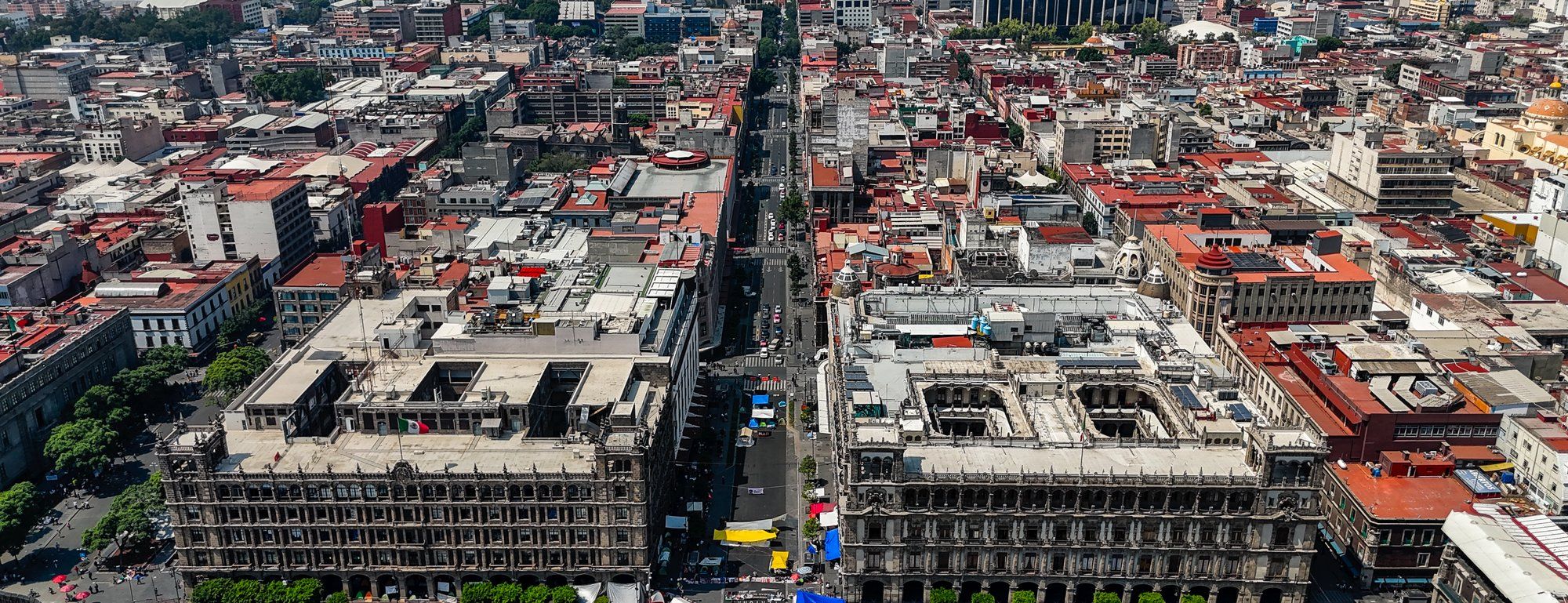 Aerial view of the Zócalo in Mexico City's historic center, with the Palacio Nacional and Antiguo Palacio del Ayuntamiento framing the plaza