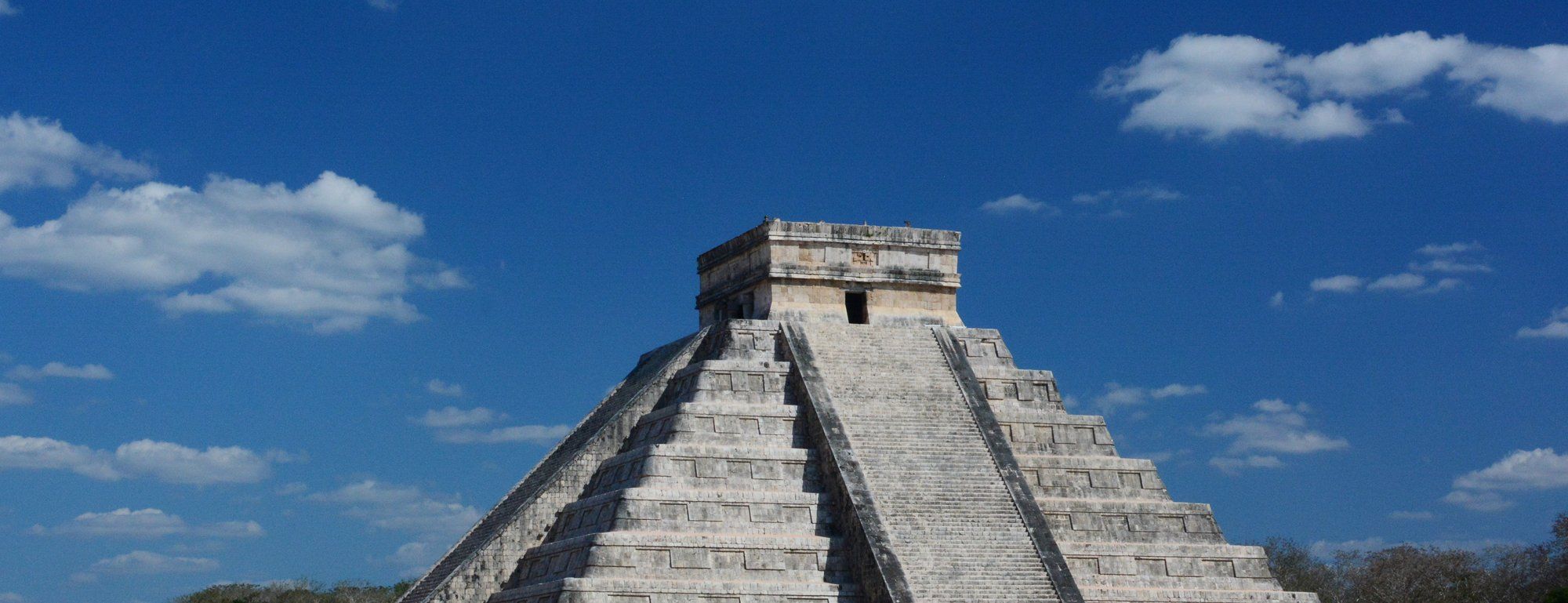 El Castillo, the stepped pyramid at the ancient Maya city of Chichén Itzá, seen against a blue sky