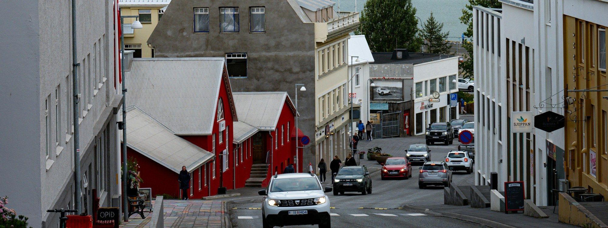 Hafnarstræti sloping past downtown Akureyri's landmark red house toward the fjord
