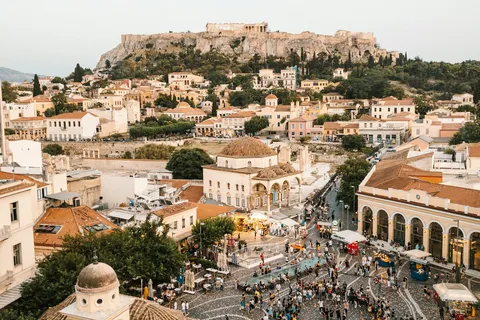 A rooftop view over Monastiraki Square's crowds and clock tower, with the Acropolis behind