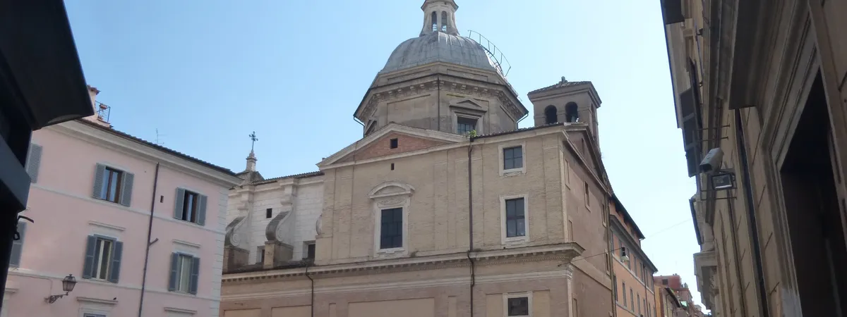 The brick and travertine dome and bell tower of a church rising above narrow streets in Rome's Monti neighborhood