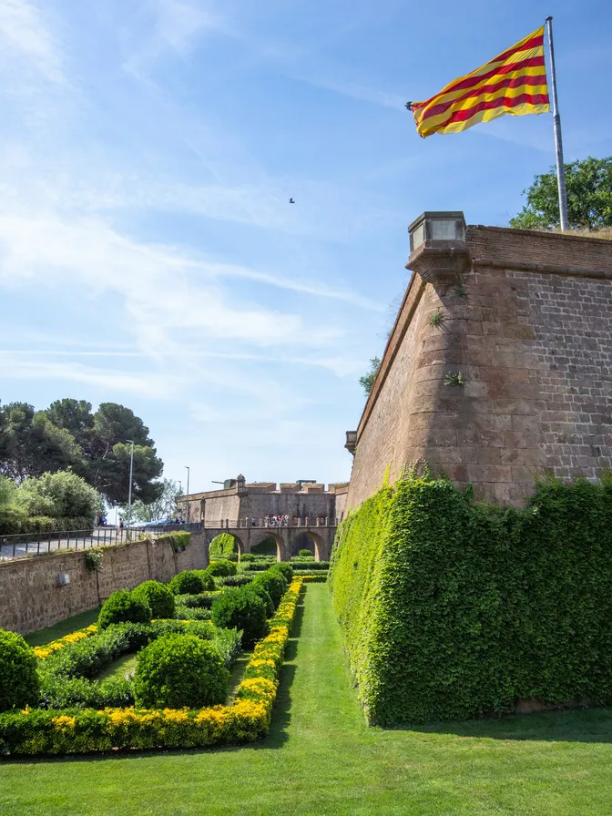 La bandera catalana ondeando sobre las murallas de piedra y los jardines del Castillo de Montjuïc