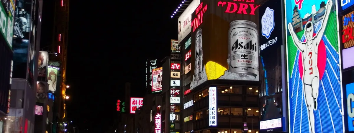 The illuminated Glico Running Man sign and neon billboards over the Dotonbori canal at night