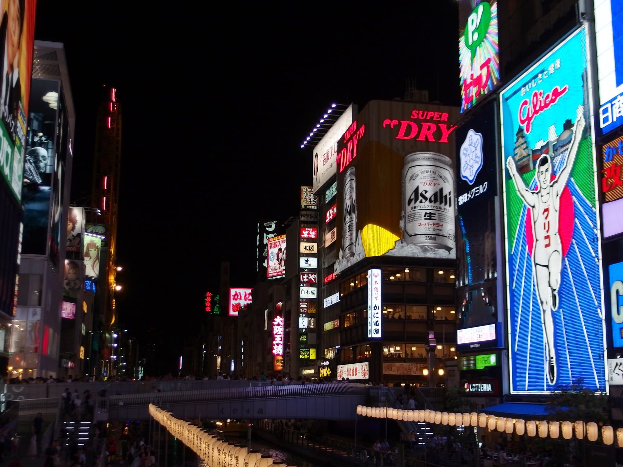 The illuminated Glico Running Man sign and neon billboards over the Dotonbori canal at night