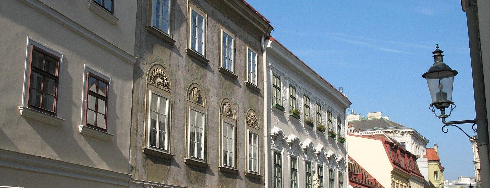 A row of pastel Biedermeier townhouses on a cobbled street in Vienna's Spittelberg quarter, Neubau