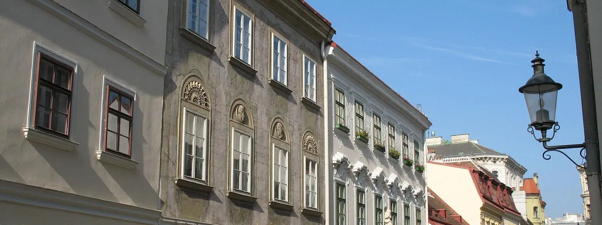 A row of pastel Biedermeier townhouses on a cobbled street in Vienna's Spittelberg quarter, Neubau