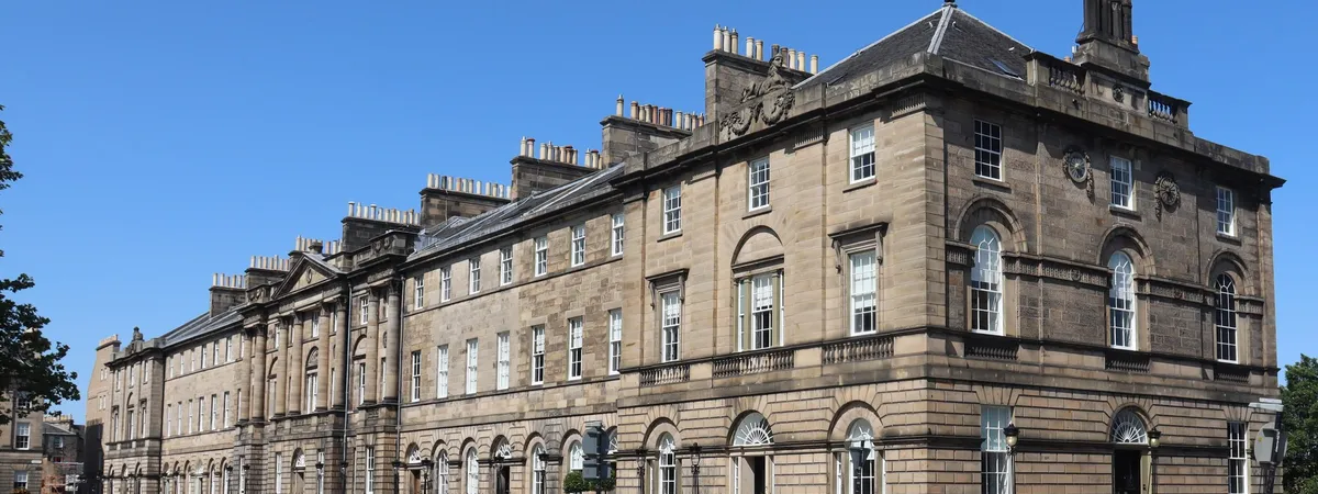 A row of Georgian townhouses on Charlotte Square in Edinburgh's New Town, seen from the street on a clear day