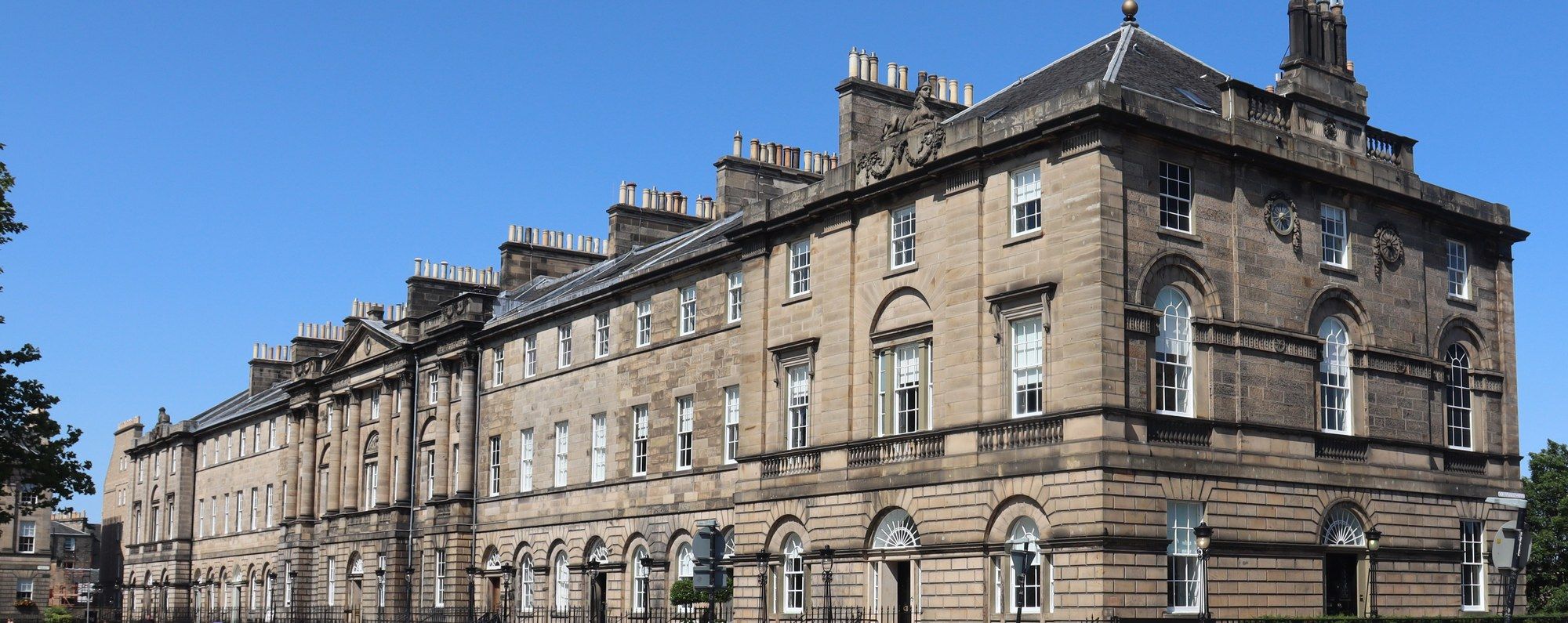 A row of Georgian townhouses on Charlotte Square in Edinburgh's New Town, seen from the street on a clear day