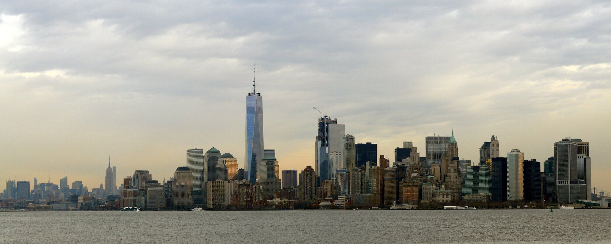 Lower Manhattan skyline seen across the Hudson River at dusk, with One World Trade Center rising above the surrounding towers