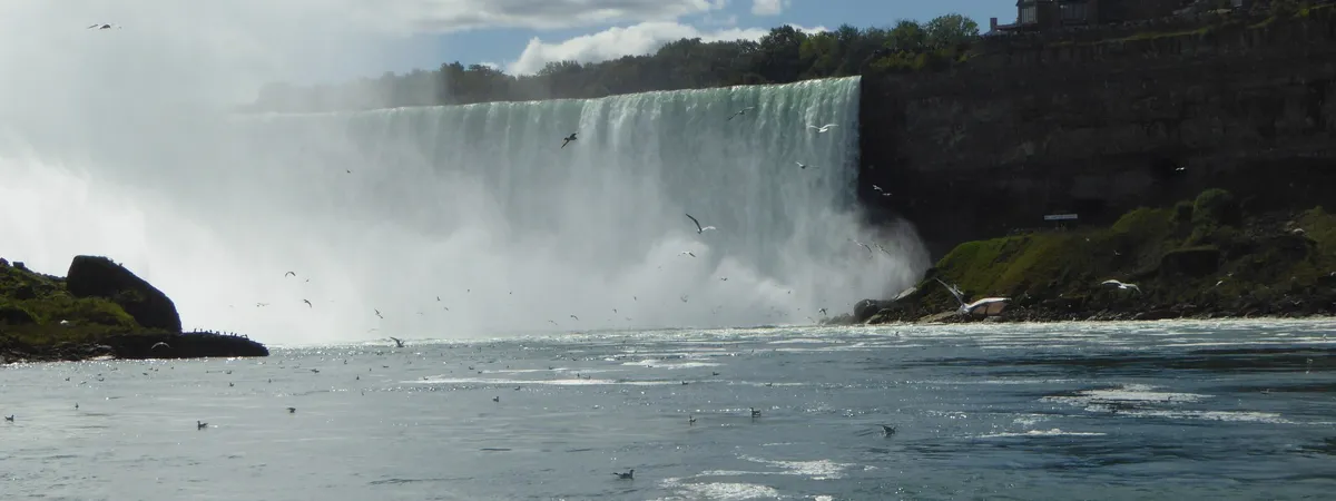 Horseshoe Falls seen from the Canadian side, with mist rising off the water and Table Rock's building on the clifftop above