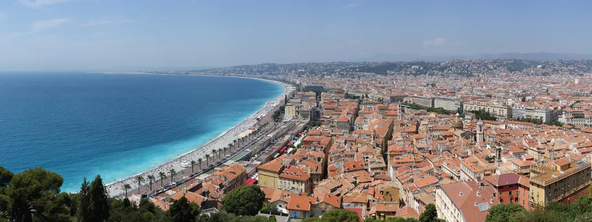 View from Castle Hill over Vieux Nice's red-tiled rooftops, the curve of the Baie des Anges, and the Promenade des Anglais