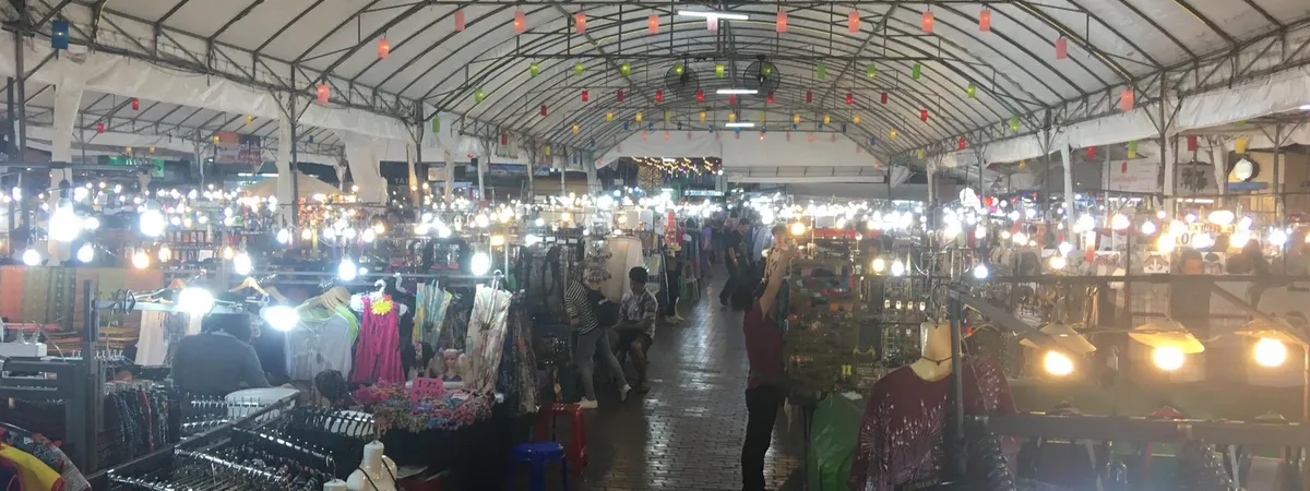 שורות של דוכני שוק מוארים תחת שביל מקורה בנייט בזאר של צ'יאנג מאי