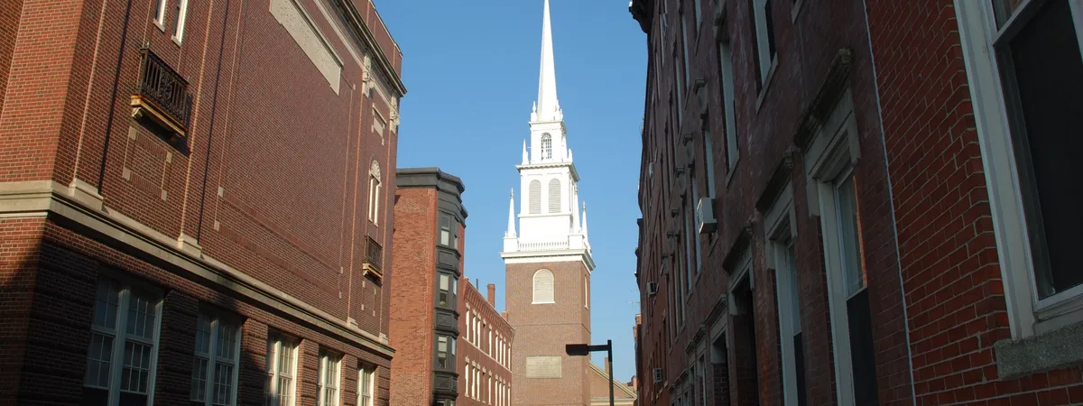 Old North Church's white steeple rising above a narrow brick lane in Boston's North End