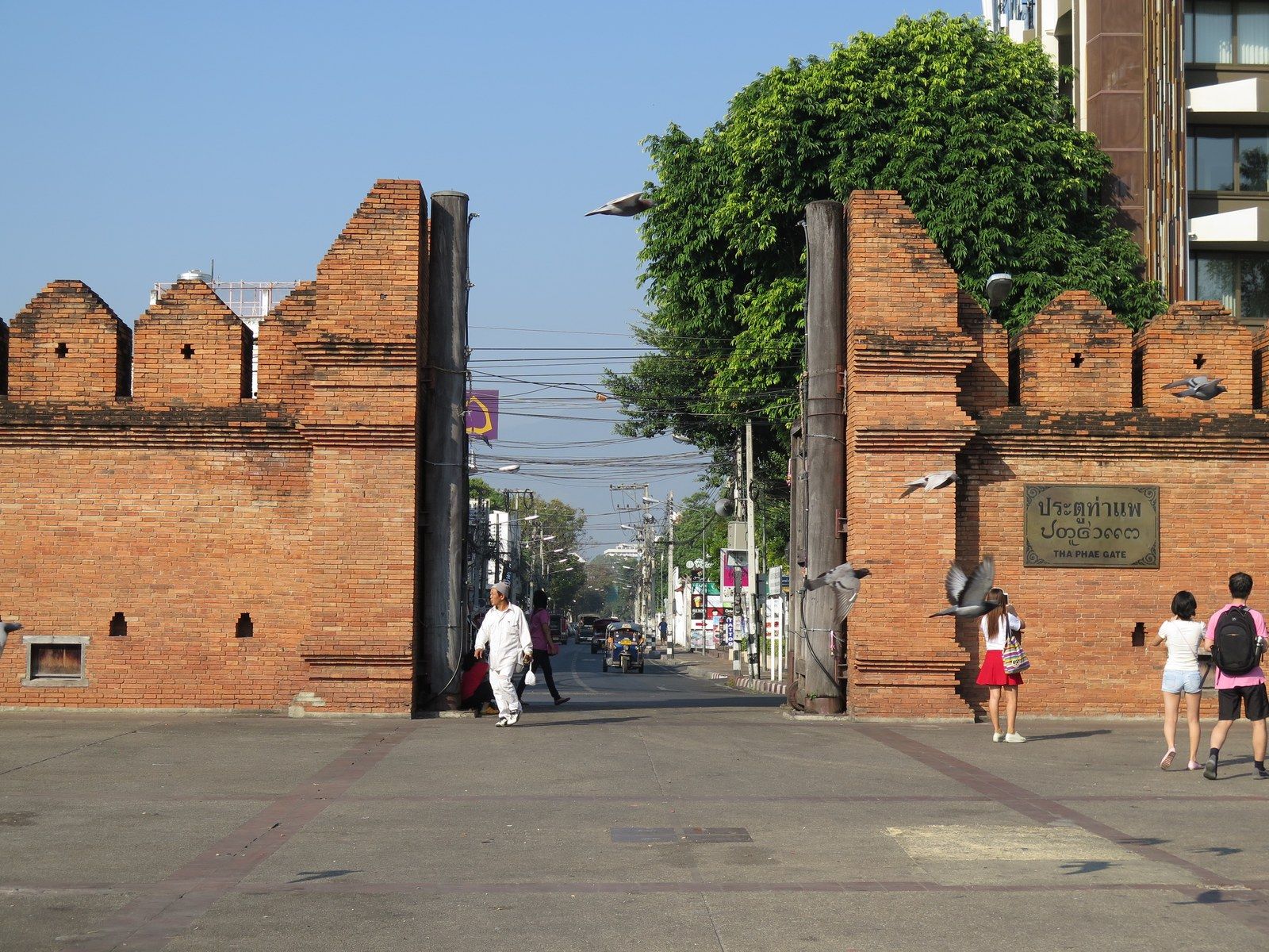 Tha Phae Gate, the red-brick eastern gate into Chiang Mai's Old City, with pigeons flying past