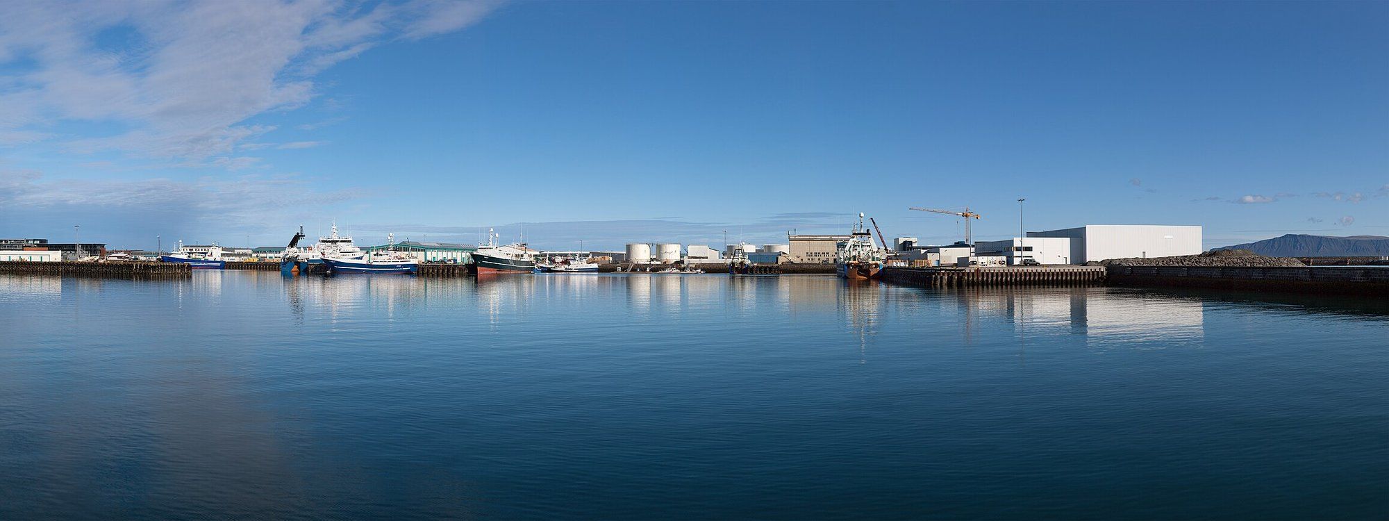 Fishing boats moored in Reykjavík's Old Harbour under a clear blue sky, with the waterfront warehouses of Grandi behind