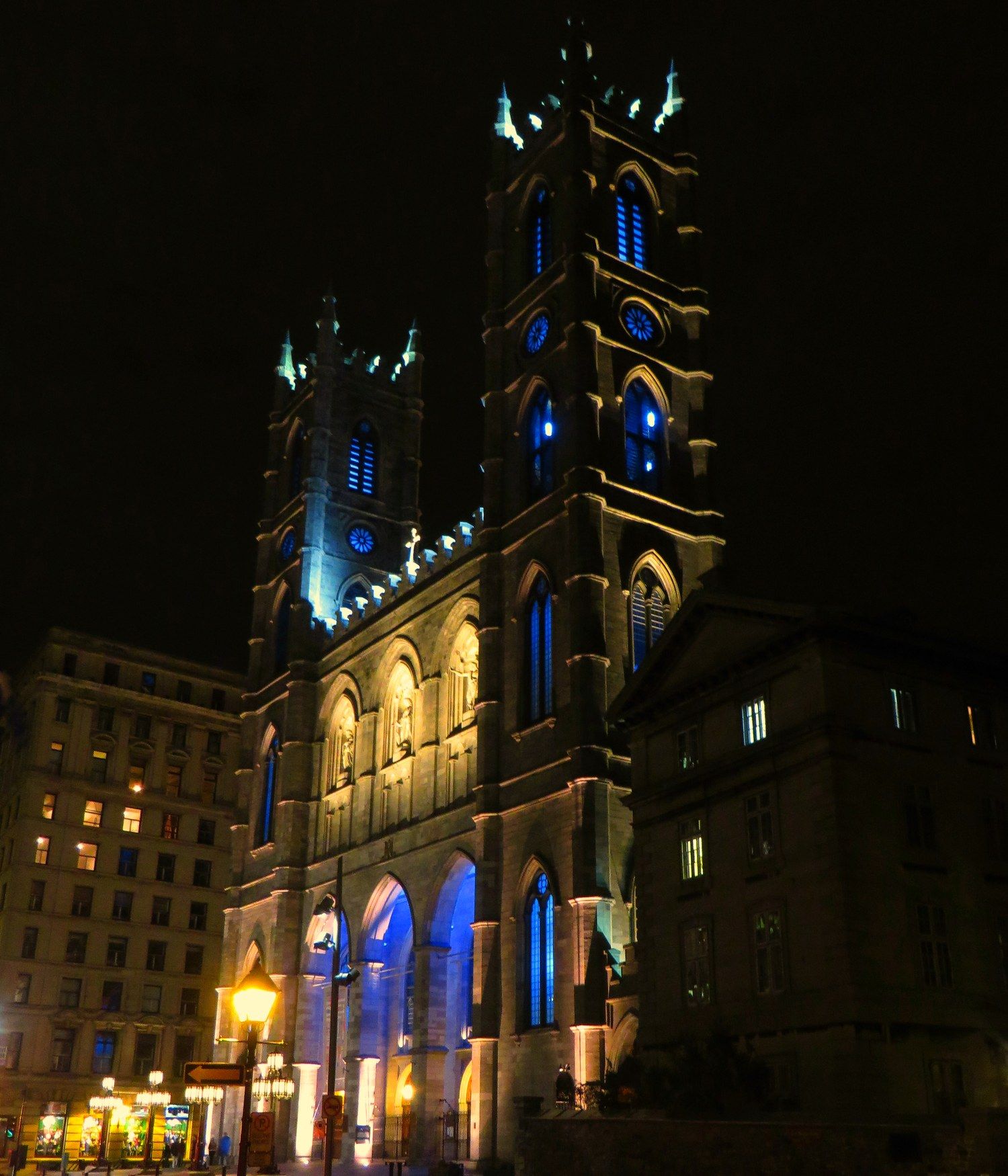 Notre-Dame Basilica's twin Gothic Revival towers lit up at night above Place d'Armes in Old Montreal