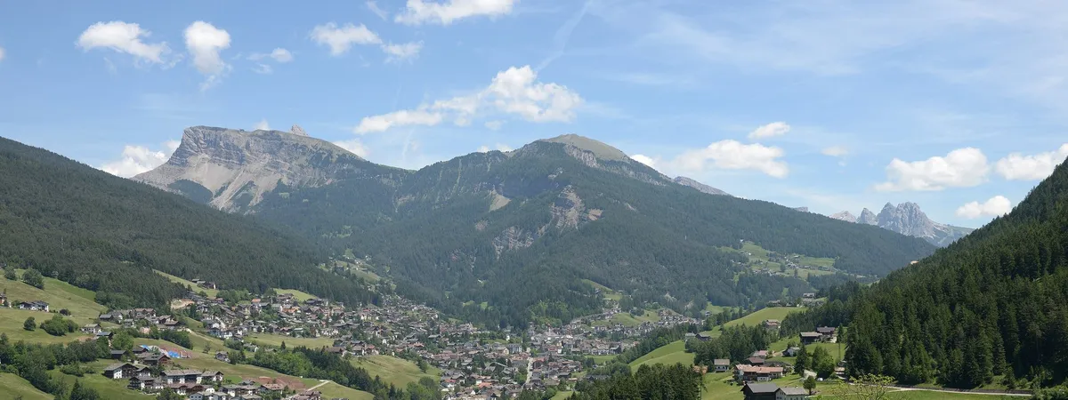 Ortisei spread across the floor of Val Gardena in summer, with wooded slopes rising to bare Dolomite peaks behind