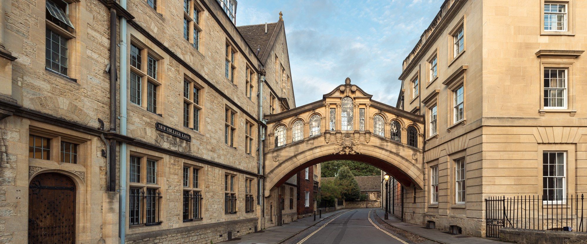 The Bridge of Sighs (Hertford Bridge) arching over New College Lane in Oxford, framed by golden-stone college buildings in morning light