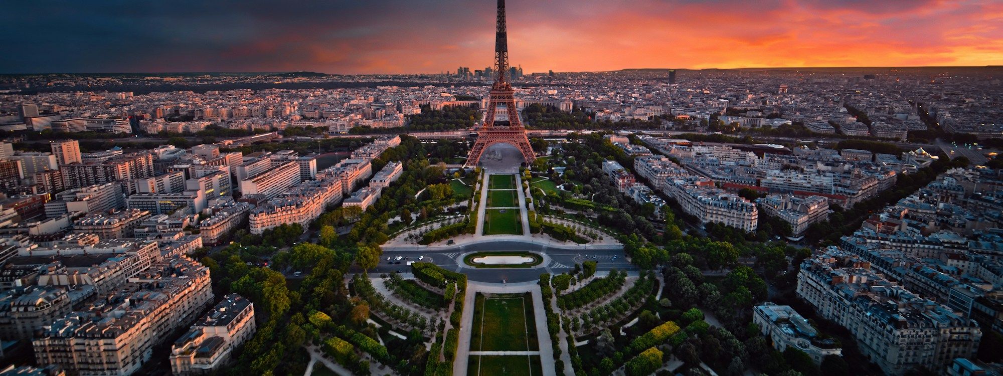 Aerial view at sunset of the Eiffel Tower rising above the Champ de Mars, with the Haussmann rooftops of Paris spreading out to the horizon