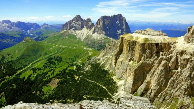 The view from the Sass Pordoi terrace across to the Sassolungo group, with the Pordoi pass road winding through the green saddle below