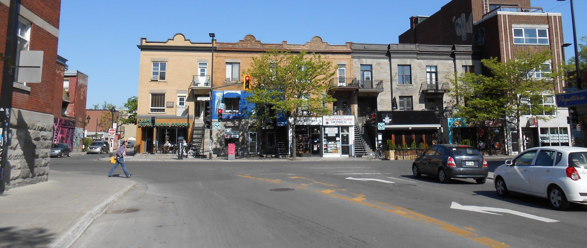 Colorful row houses and street-level cafés along Avenue du Mont-Royal at its intersection with Rue Saint-Hubert in the Plateau