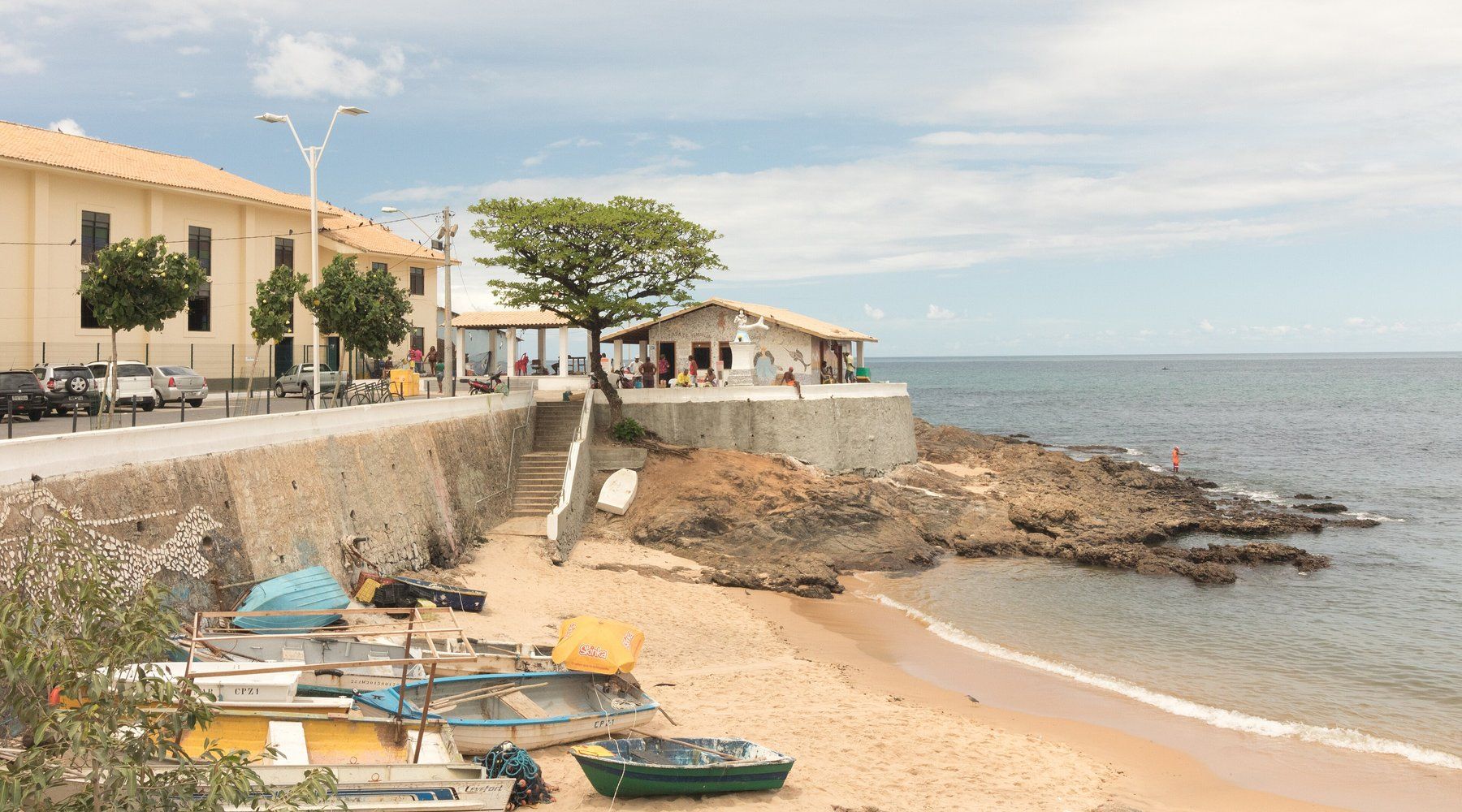 El pequeño santuario encalado de Casa de Iemanjá sobre un promontorio rocoso frente al mar en Rio Vermelho, con barcas de pesca varadas en la playa cercana