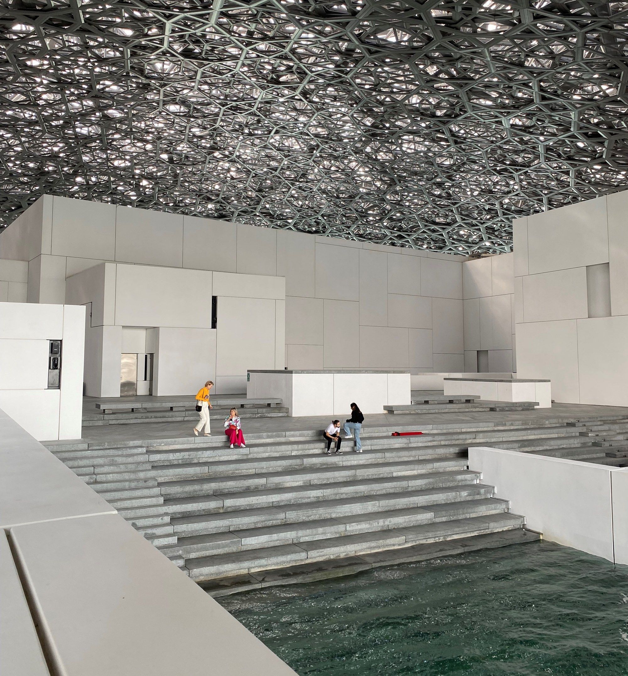 The perforated geometric dome of the Louvre Abu Dhabi, letting patterned light fall onto the plaza below