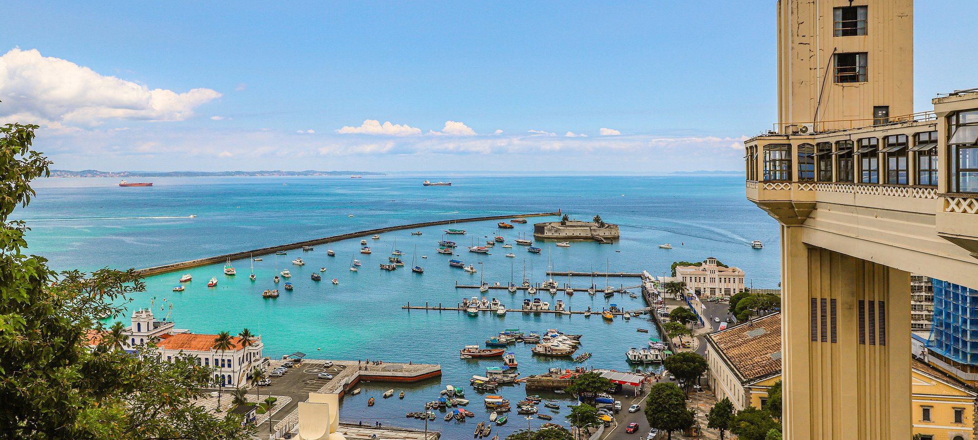 El Elevador Lacerda elevándose sobre el puerto de Salvador, con barcos de pesca anclados en las aguas turquesa de la Bahía de Todos los Santos