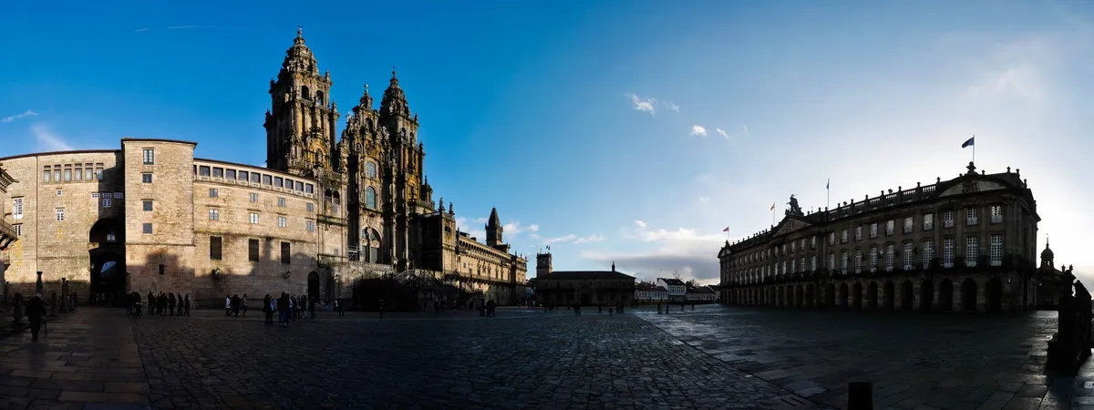 The Baroque towers of Santiago de Compostela Cathedral seen across Praza do Obradoiro at dusk, with the Pazo de Raxoi to the right