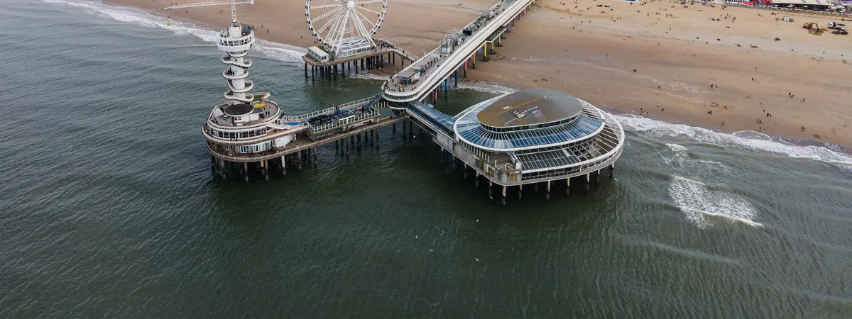 Aerial view of Scheveningen Pier with its Ferris wheel and bungee tower extending into the North Sea beside the beach