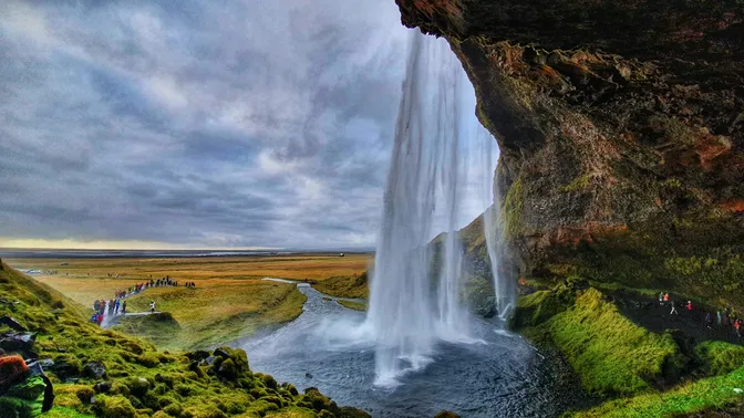 The view from behind Seljalandsfoss's curtain of falls, looking out over Iceland's south coast plain