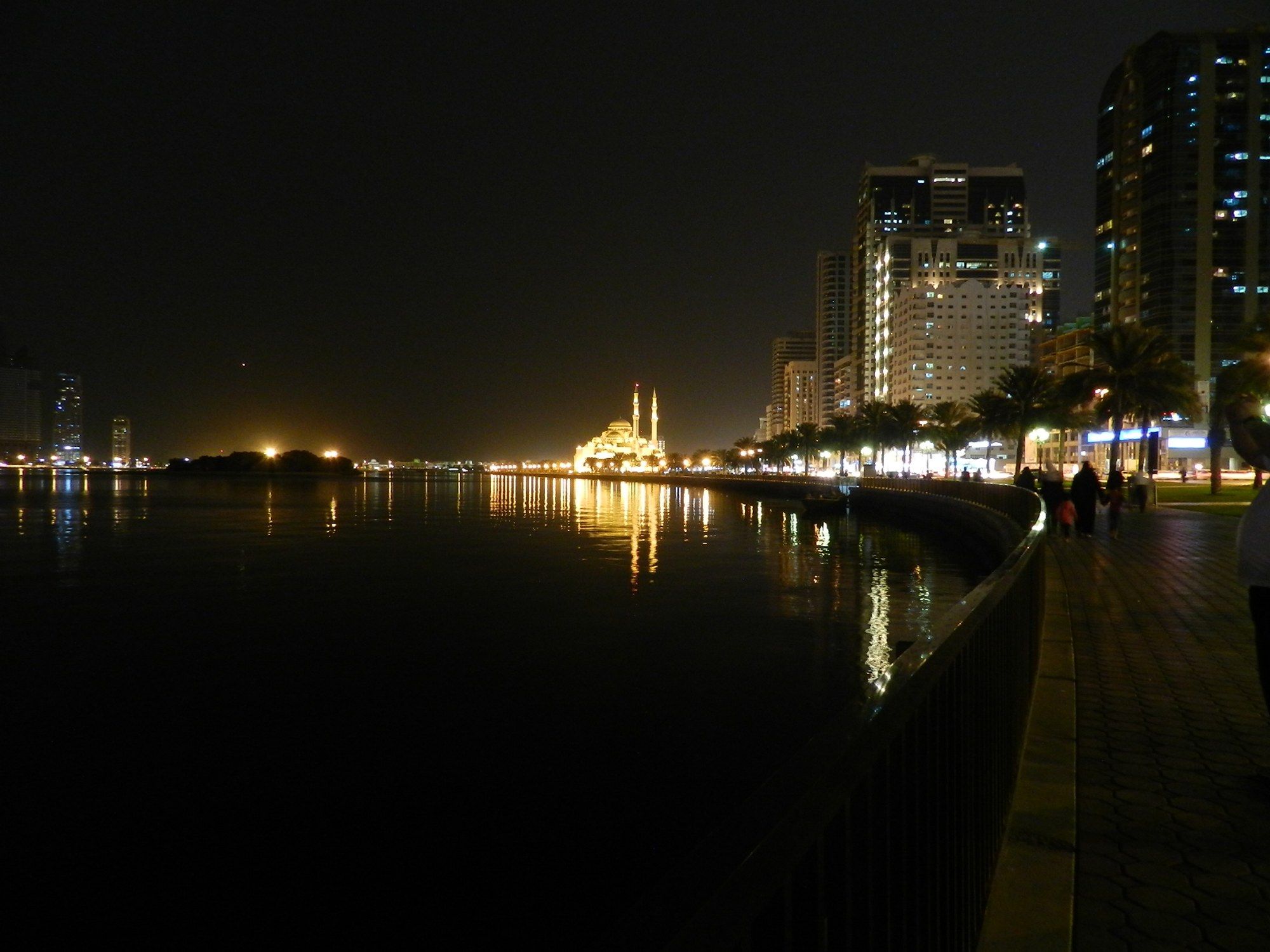 Al Noor Mosque lit up at night, reflected in the water of Khalid Lagoon along Sharjah's Corniche