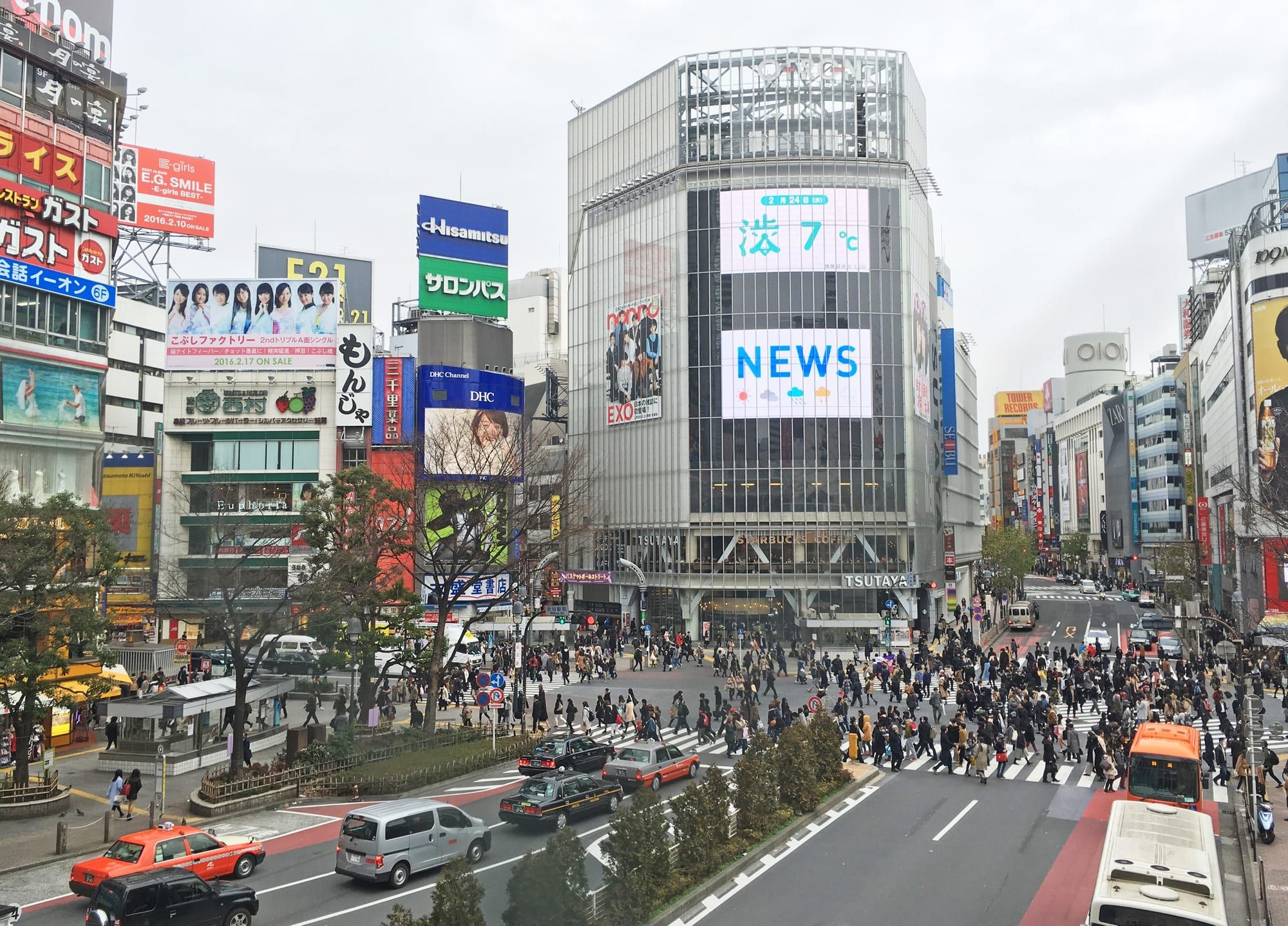 Crowds crossing the Shibuya Scramble Crossing surrounded by illuminated billboards