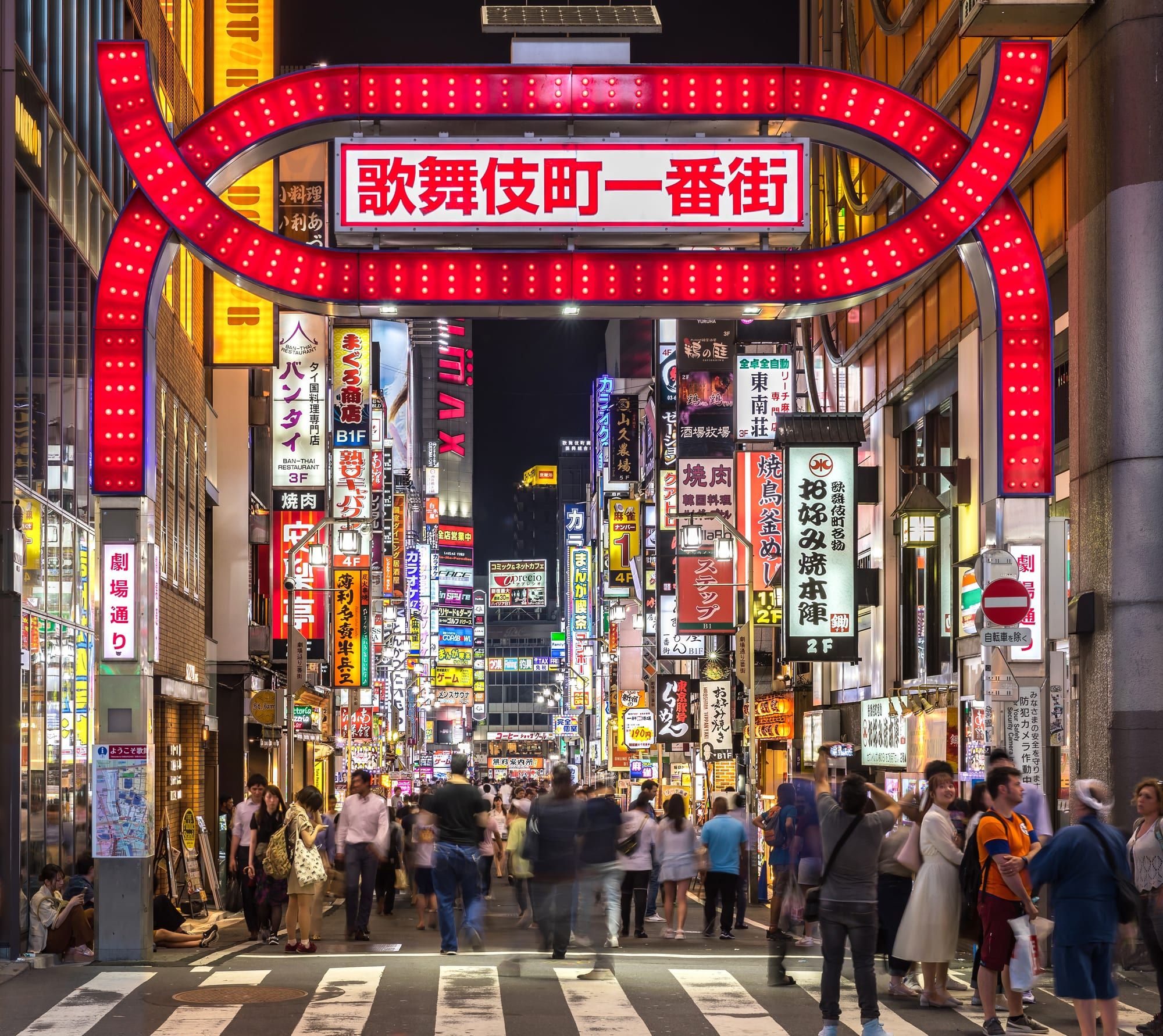The red torii-style gate and neon signs of Kabukicho at night in Shinjuku