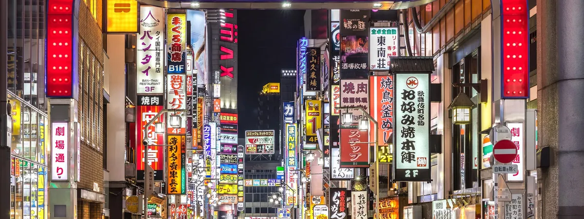The red torii-style gate and neon signs of Kabukicho at night in Shinjuku