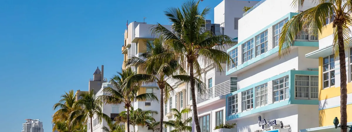 Pastel-colored Art Deco hotels, including the Penguin Hotel, lining Ocean Drive in South Beach behind a row of palm trees